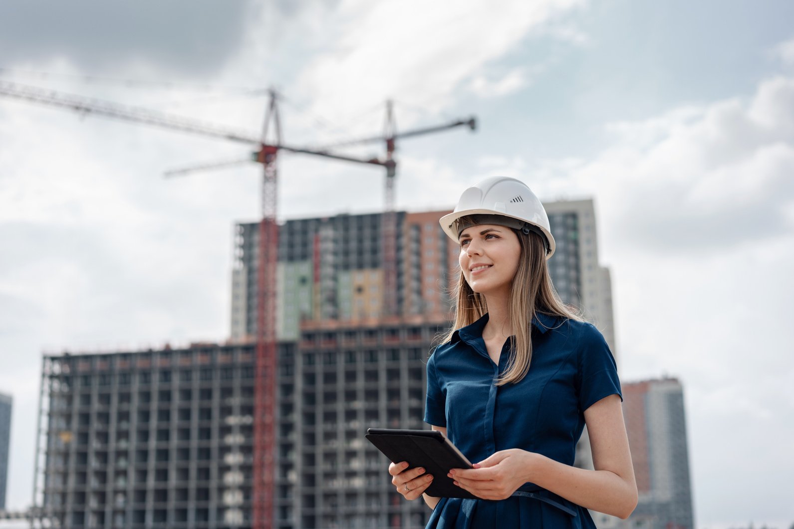 Female construction engineer. Architect with a tablet computer at a construction site. Young Woman looking, building site place on background. Construction concept